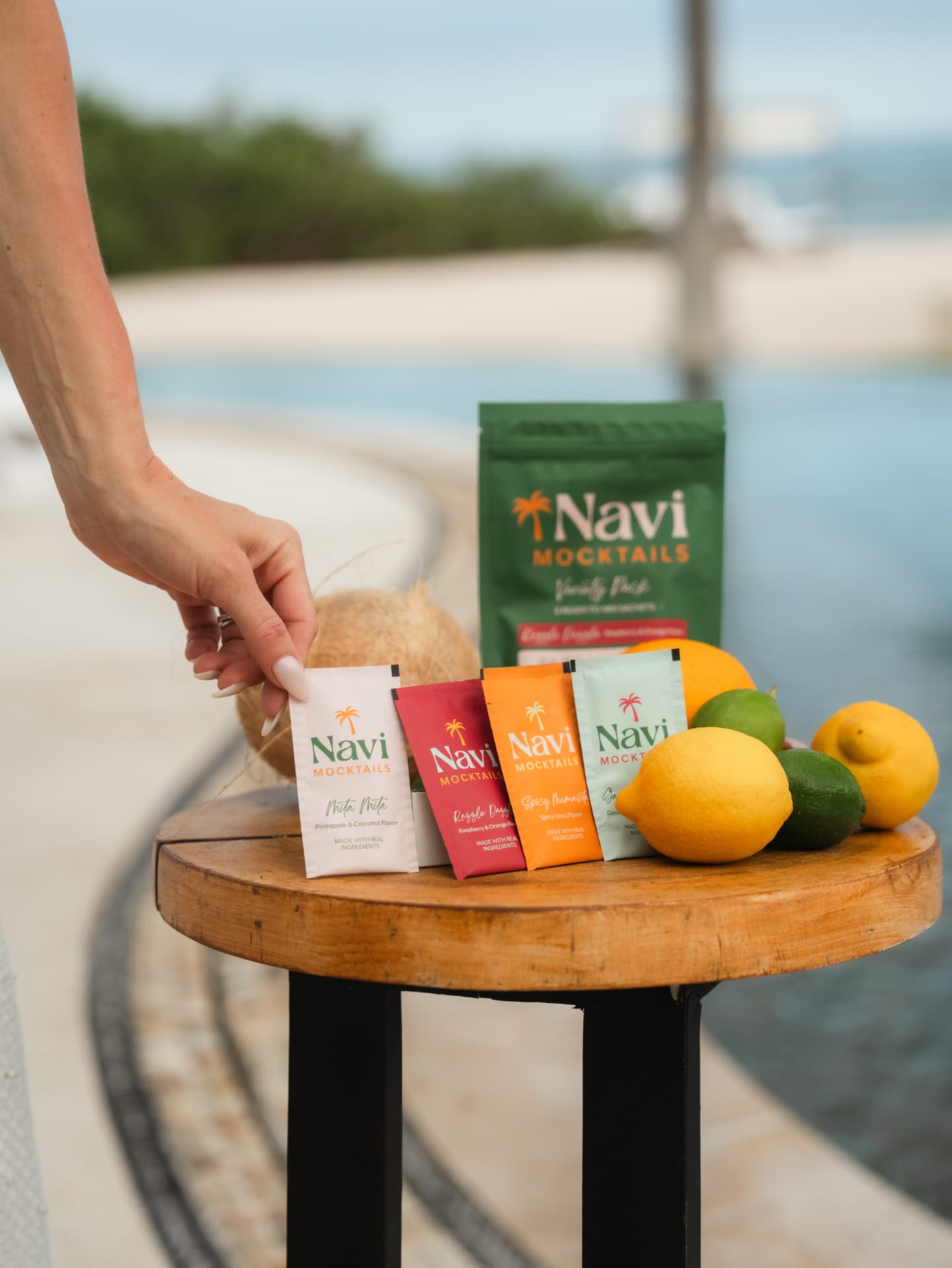 Navi sachets arranged poolside with fresh citrus and a poured mocktail